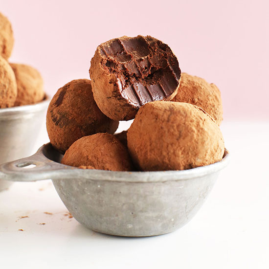 Half eaten Dark Chocolate Vegan Truffle stacked atop more truffles