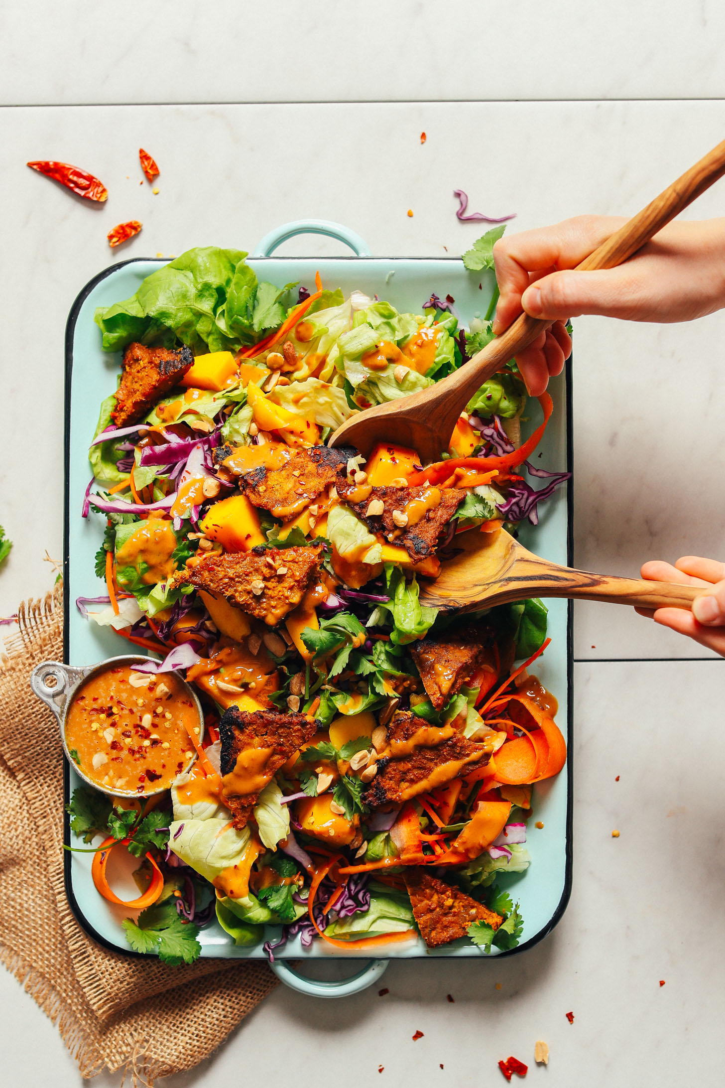 Grabbing a serving of Mango Green Salad with Creamy Peanut Dressing for a refreshing plant-based lunch