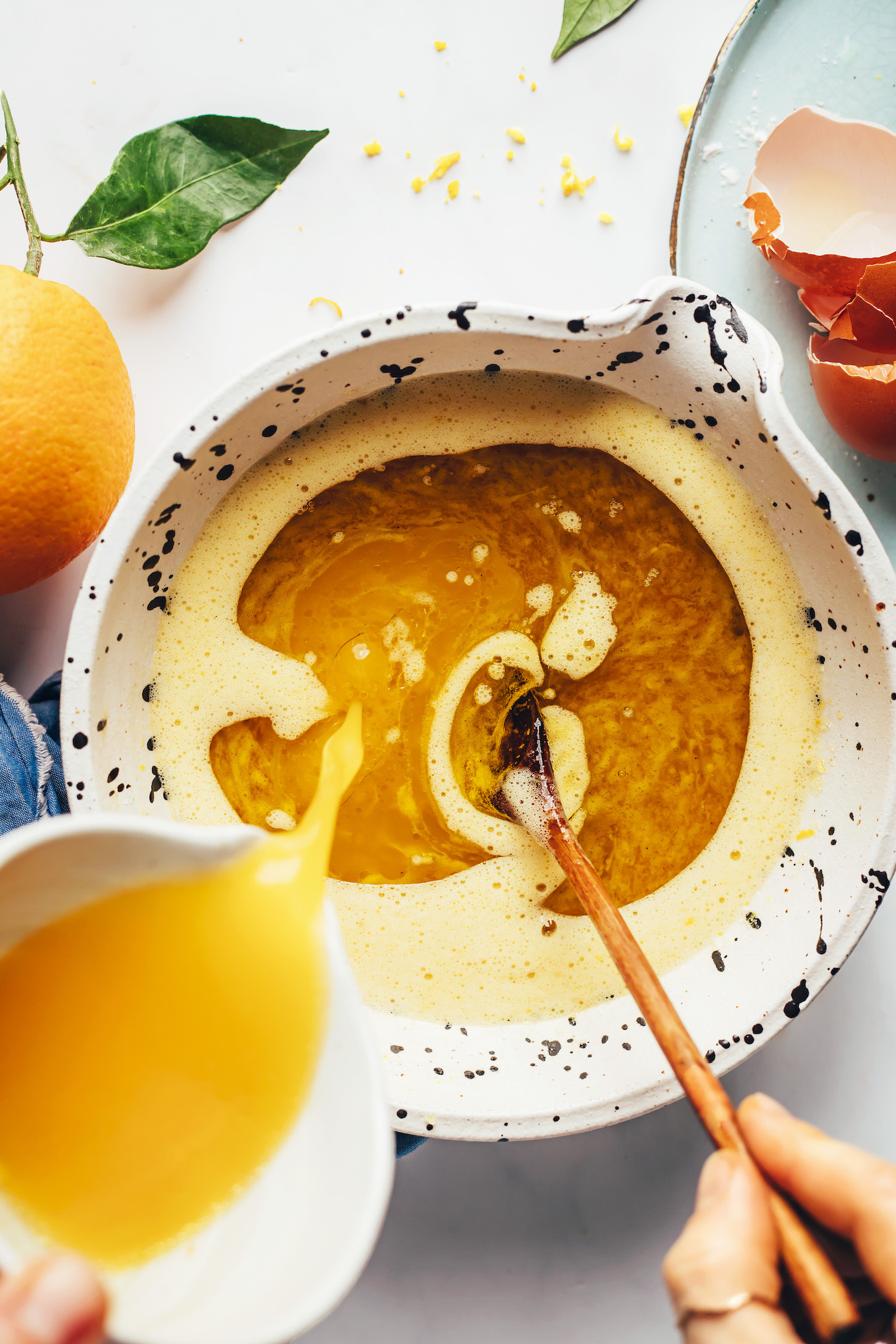 Pouring orange juice into a bowl with other wet ingredients