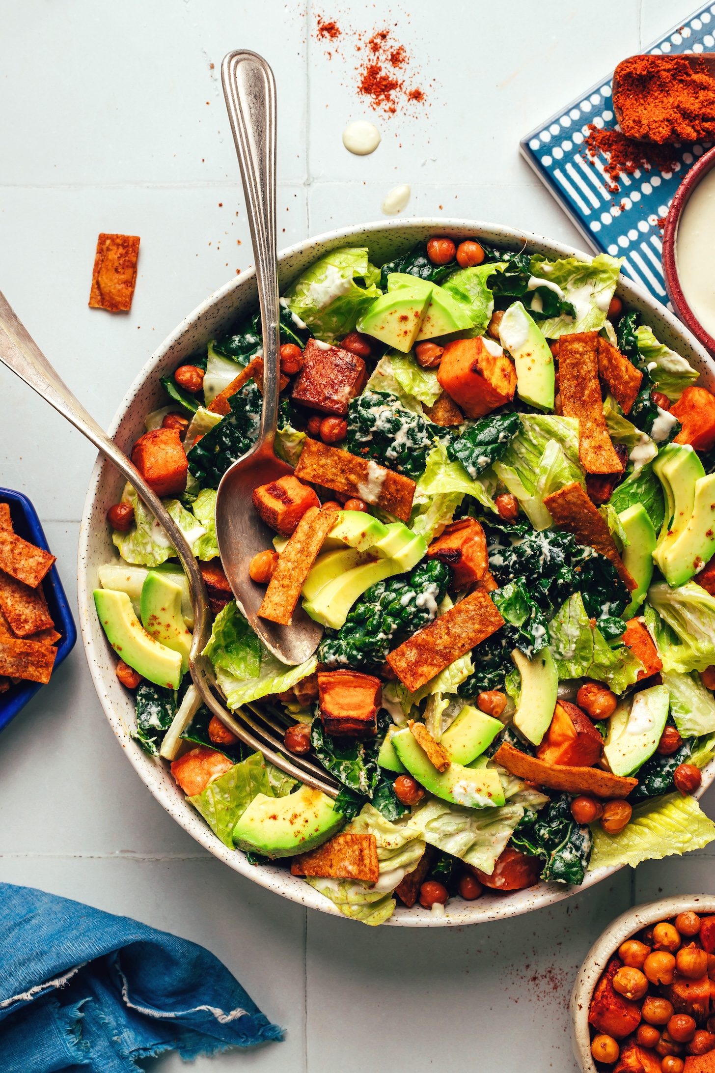 Serving spoon and fork resting in a bowl of our vegan sweet potato chickpea taco salad